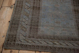 Corner view of a vintage rug's multi-tiered borders in charcoal brown and dusty powder blue.