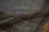 A soft fold in the vintage rug reveals its heavy abrashes and distressed, low-pile texture.