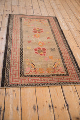 Antique Ningxia rug corner with red running-T border, floral motifs, and natural wear.