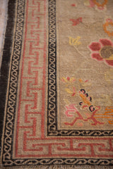 Antique Ningxia rug corner with pink reciprocating running-T border and charcoal band.