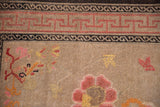 Antique Chinese Ningxia rug detail: pink running-T border, charcoal elements, and worn beige field with blooming branches.