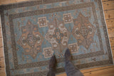 Overhead view of the distressed Hamadan rug's soft sky blue and beige geometric pattern.
