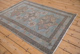 Angled perspective of a distressed Hamadan rug with a soft blue field and geometric medallions.