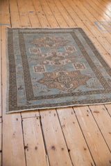 Angled view of a vintage Hamadan rug with a low pile and geometric sky blue design.