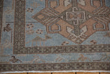 Close-up of a distressed Hamadan rug's low pile, showing the geometric border and pinwheel florals.