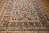 Vintage distressed Anatolian rug viewed at an angle, showing the germinating blossom border in detail.