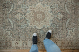 Distressed vintage Tabriz rug showing its medallion in muted dusty teal, blue, and brown.