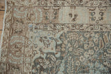 Corner detail showing the distressed, worn pile on a vintage Tabriz floral rug.