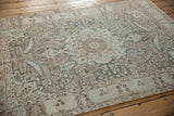 Angled view of the distressed Tabriz rug's soft, time-softened palette of teal and brown.