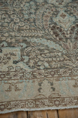 Corner detail of a distressed Tabriz rug's intricate border with a low, textured pile.