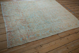 Angled view of a distressed Afshar rug detailing the machine-bound side and worn, low pile texture.
