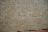 Detailed texture of a distressed Persian rug showing low pile and pale terra cotta and blue botehs.