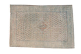 Vintage distressed Arak rug with a diamond medallion in muted ivory, dusty blue, and terracotta.