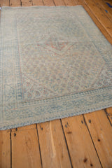 Worn texture of a vintage Arak rug with dusty blue borders and terracotta boteh motifs.