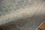 Angled close-up of a distressed Arak rug revealing its low pile and exposed cotton foundation.