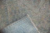 Hand-knotted foundation in blue and ivory beneath the distressed low pile with visible wear.