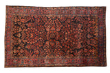 Antique Mohajeran Sarouk rug with dense floral sprays in raspberry red and blue on a dark navy blue field.
