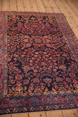 A perspective view of an antique Sarouk rug's intricate floral sprays and raspberry palmette border.