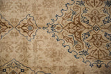 Rococo-stylized leaves outlined in sapphire blue on the distressed, short pile of a vintage Tabriz carpet.