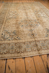 Angled view showing the floral cartouche border and corner spandrel on a distressed vintage Tabriz carpet.