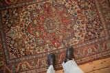 Antique Kashan rug detail: cherry red field, sapphire blue floral arabesques, visible knot heads.