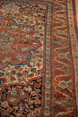 Intricate floral vines and sapphire blue blossoms on an antique Kashan rug's cherry red border.