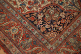 Intricate cherry red border and navy blue field with time-softened floral vines on this antique Persian Kashan.