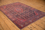 Antique Sarouk rug from an elevated angle, showing its traditional medallion and floral composition.