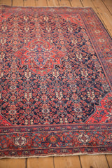 Angled view of an antique Sarouk rug's low pile, highlighting the red medallion and navy field.