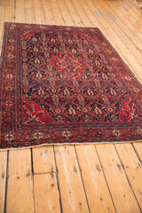 Perspective view of an antique Sarouk rug's intricate medallion and deep navy blue floral field.
