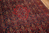 Concentric red shield medallion on the navy blue henna-motif field of an antique Persian Sarouk rug.