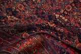 Textured low pile of an antique Sarouk rug with intricate floral motifs in navy blue and madder red.