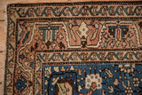 Corner detail of a vintage Arak rug showing the meandering vine border in dusty rose and sand.
