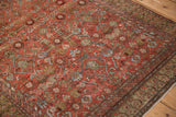 Corner view of an antique Malayer rug's henna plant border and evenly worn Herati field in chestnut and blue.