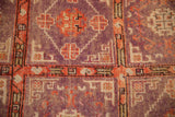 Detail of the distressed, low pile showing geometric patterns in aubergine and faded tomato red.