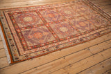 Distressed vintage Khotan rug shown at an angle, revealing its full geometric lattice pattern.