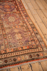 Angled view of a vintage Khotan rug's geometric lattice design in pale aubergine, violet, and faded tomato red.