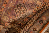 Softly folded vintage Khotan rug revealing a low, textured pile in aubergine and tomato red.