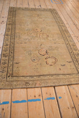Angled view of the full distressed Karabagh rug showing its sandy color and elongated form.
