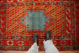Overhead view of an antique Anatolian rug's geometric blue medallion and red boteh-filled field.