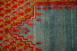 A stepped red outline borders the abrashed blue field of an antique Anatolian rug with a worn, low-pile texture.