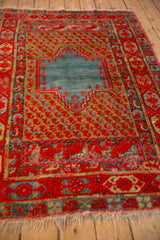 Angled perspective of an antique Anatolian rug's abrashed blue medallion and red boteh field.