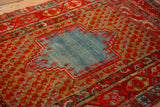 Angled view of an antique Anatolian rug's worn, abrashed blue medallion and ochre boteh field.