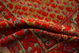 Close-up of the antique rug's soft pile in red and ochre, with visible knot heads.