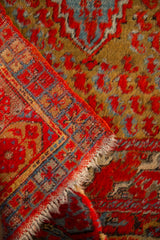 Folded corner of an antique Anatolian rug showing its hand-knotted texture and tattered end.