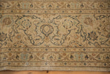 Close-up of the scrolling vine border on a distressed Kashan carpet with a time-softened patina.