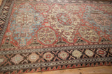 Perspective across an antique Soumac carpet, detailing its brick red medallions and crab style border.