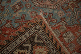 Folded corner of an antique Soumac revealing its dark wave border and blue geometric field.