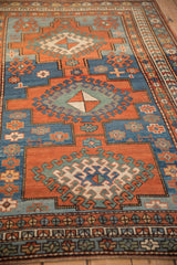Kazak rug's geometric medallion and hook motifs, displaying madder red and sapphire blue.