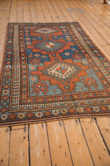 Antique Kazak rug corner with triple geometric borders in madder red and sapphire blue.
